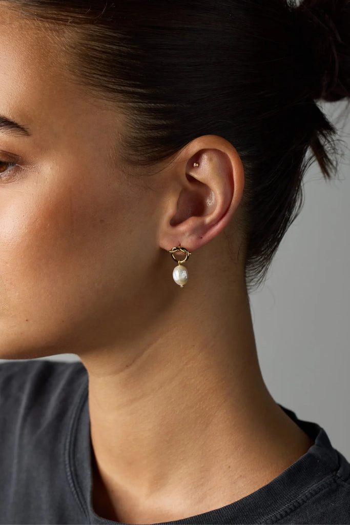 Alice earring - Gold-Zafino-These earrings feature a freshwater pearl delicately hanging from a meticulously crafted gold knot, elegantly attached to a stylish stud. The intricate gold knot adds a touch of sophistication and refinement to the overall design. Metal: 18K Gold Plated on BrassDimensions: 13mm x 22mmWater Resistant: Splash proof, not recommended to be worn in the ocean or pool Water resistant Hypoallergenic & Nickel Free Female Founded & Family Owned-Pash + Evolve