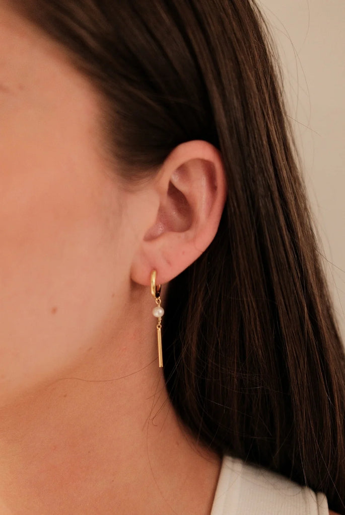 Isabelle earring - Gold-Zafino-The Isabelle Earring is a refined blend of modern minimalism and timeless elegance. Featuring a classic gold huggie adorned with a delicate freshwater pearl and a sleek bar drop, this design moves effortlessly with you—adding a touch of sophistication to both everyday wear and evening looks. Metal: 18K Gold Plated on BrassDimensions: 8mm Hoop, 40mm DropWater Resistant: Splash proof, not recommended to be worn in the ocean or pool Freshwater Pearl Water resistant Hypoallergenic