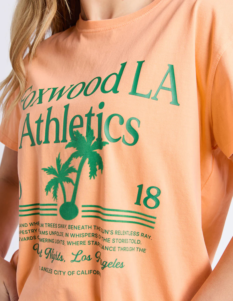 La Aths Tee - Peach-Foxwood-The LA Aths Tee brings a fun, sporty edge to your casual look. Made from soft 100% cotton, it features an exclusive Foxwood front chest print with bold lettering and a palm graphic. Designed with a round neckline and relaxed fit, it’s an easy style for everyday wear. Foxwood exclusive front chest print Round neckline Relaxed fit 100% Cotton Model is wearing a size 10-Pash + Evolve