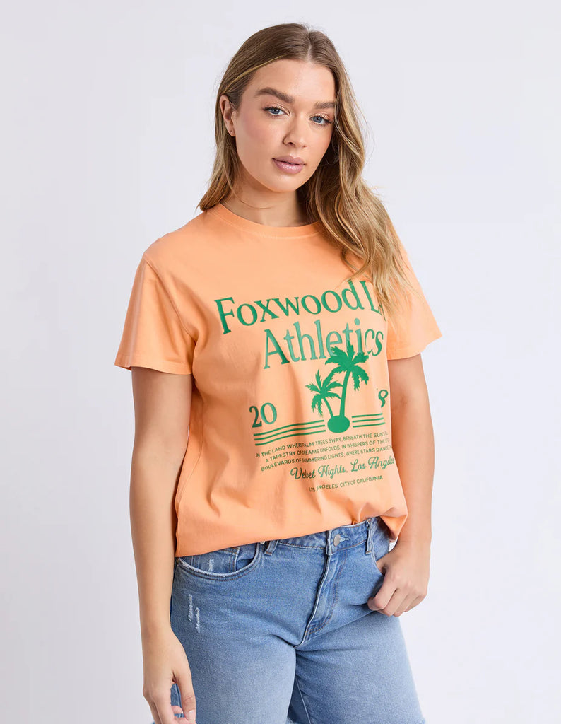 La Aths Tee - Peach-Foxwood-The LA Aths Tee brings a fun, sporty edge to your casual look. Made from soft 100% cotton, it features an exclusive Foxwood front chest print with bold lettering and a palm graphic. Designed with a round neckline and relaxed fit, it’s an easy style for everyday wear. Foxwood exclusive front chest print Round neckline Relaxed fit 100% Cotton Model is wearing a size 10-Pash + Evolve
