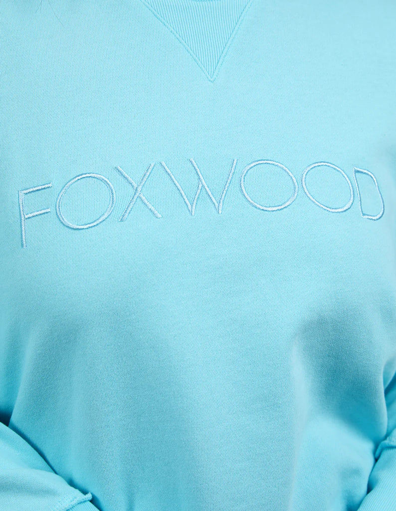 Simplified Crew - Light Blue-Foxwood-The Simplified Crew is the perfect throw over for your everyday wardrobe. With its round neck, hi-lo hemline, side splits with raw edging & the classic Foxwood logo, you are going to want one in every colour. Front chest embroidery Raw edge detail Curved hem 100% Cotton Our model is 176cm and wears Size 10-Pash + Evolve