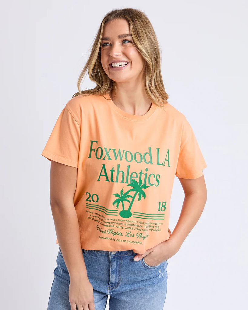 La Aths Tee - Peach-Foxwood-The LA Aths Tee brings a fun, sporty edge to your casual look. Made from soft 100% cotton, it features an exclusive Foxwood front chest print with bold lettering and a palm graphic. Designed with a round neckline and relaxed fit, it’s an easy style for everyday wear. Foxwood exclusive front chest print Round neckline Relaxed fit 100% Cotton Model is wearing a size 10-Pash + Evolve
