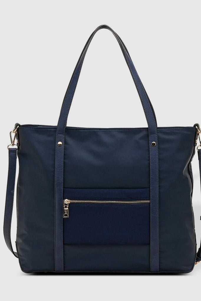 Nora Nylon Tote Bag - Navy-Louenhide-The Louenhide Nora Navy Nylon Tote Bag is the perfect combination of practicality and style. With its spacious interior, this tote bag is perfect for carrying your daily essentials. It features one zip pocket and two slip pockets in the main compartment, as well as a backside zip pocket and feet on the base to keep your belongings safe and secure. The backside suitcase sleeve allows you to easily attach the tote to your luggage for added convenience. The adjustable and d